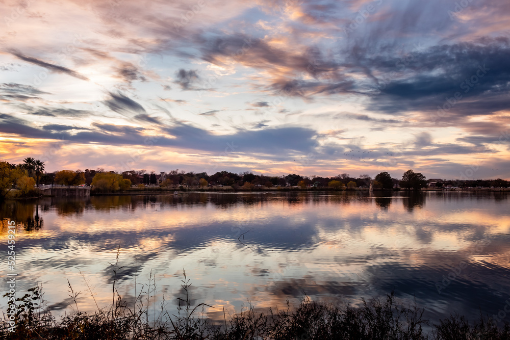Dramatic pink and purple sunset clouds reflection on Woodlawn Lake San Antonio Texas