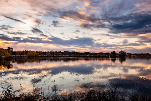 Fototapeta Naklejka Na Ścianę i Meble -  Dramatic pink and purple sunset clouds reflection on Woodlawn Lake San Antonio Texas