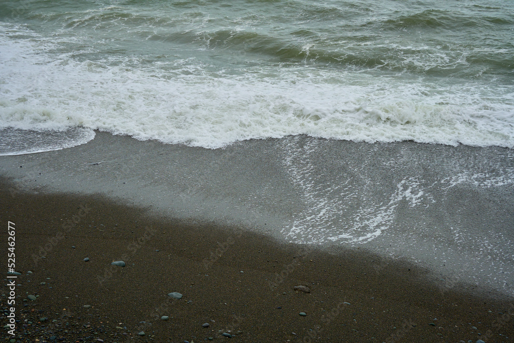 Sea shore with pebbles, wet sea pebbles on the beach and quiet sea surf Sea shore with pebbles, wet sea pebbles on the beach and quiet sea surf