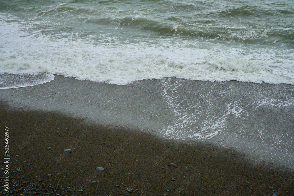 Sea shore with pebbles, wet sea pebbles on the beach and quiet sea surf