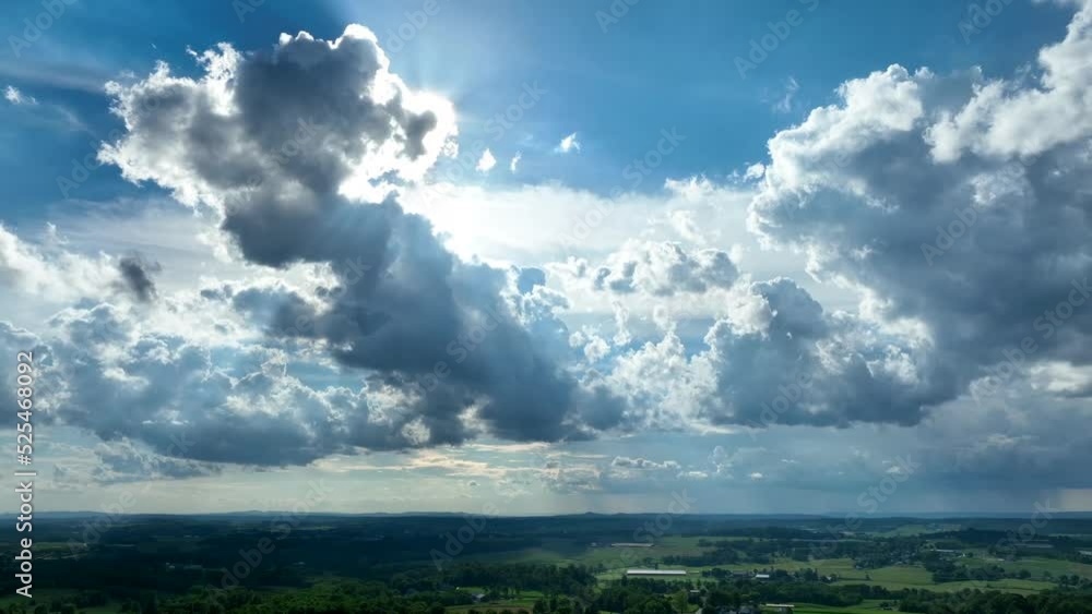 Beautiful cloud formation in sky, backlit by sun. Green rural fields below. Aerial view. Beautiful cloud formation in sky, backlit by sun. Green rural fields below. Aerial view.