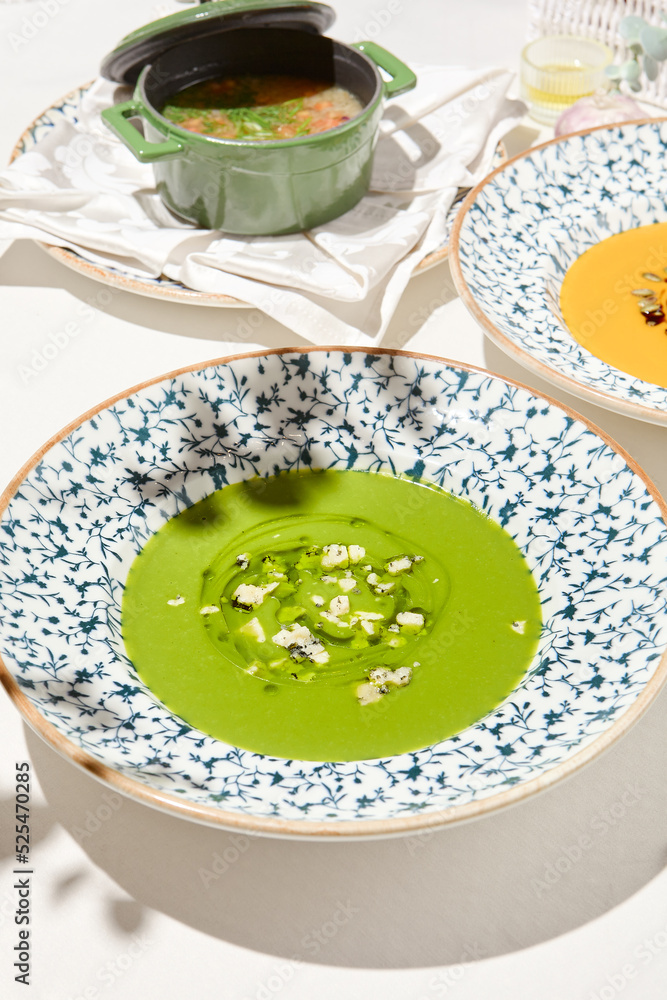 Composition with vegetable soup in ceramic bowl. Green soup with broccoli and cheese on summer day. Italian soup with green pea. Vegan menu. Hot dishes. Vegetables food. Eat less meat. Composition with vegetable soup in ceramic bowl. Green soup with broccoli and cheese on summer day. Italian soup with green pea. Vegan menu. Hot dishes. Vegetables food. Eat less meat.