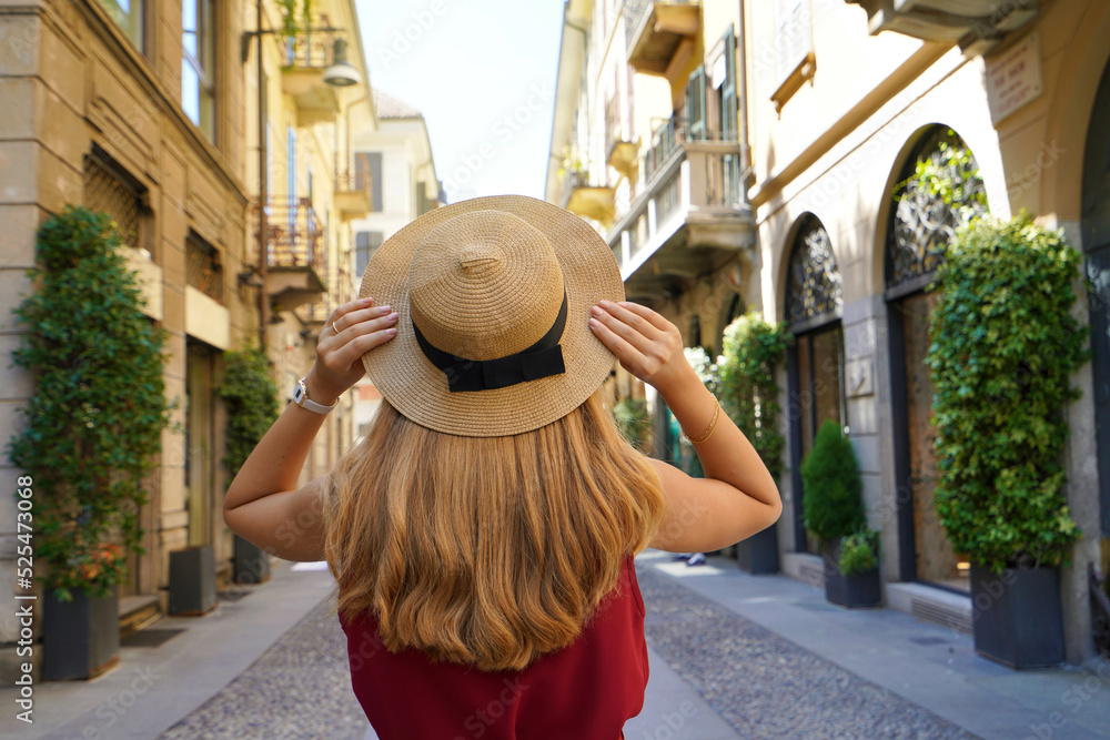 Fashion girl discovering Milan, Italy. Back view of stylish young woman holds hat in Brera district, Milan, Italy.