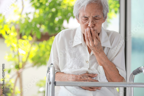 Asian senior woman with stomachache,old elderly holding her abdomen,covering mouth with hand,discomfort in the stomach associated with difficulty in digesting food,indigestion after eating fastfood
