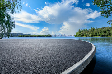Asphalt road platform and lake with city skyline background