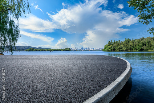 Asphalt road platform and lake with city skyline background
