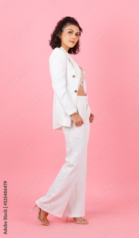 Portrait studio shot of Asian sexy curly hairstyle professional successful businesswoman in white fashionable casual suit with lace lingerie crop top bra standing look at camera on pink background Portrait studio shot of Asian sexy curly hairstyle professional successful businesswoman in white fashionable casual suit with lace lingerie crop top bra standing look at camera on pink background