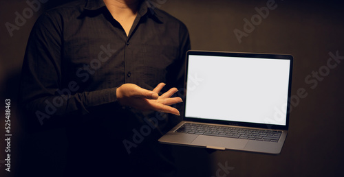 Portrait of a professional hacker using a laptop in a dark background room.