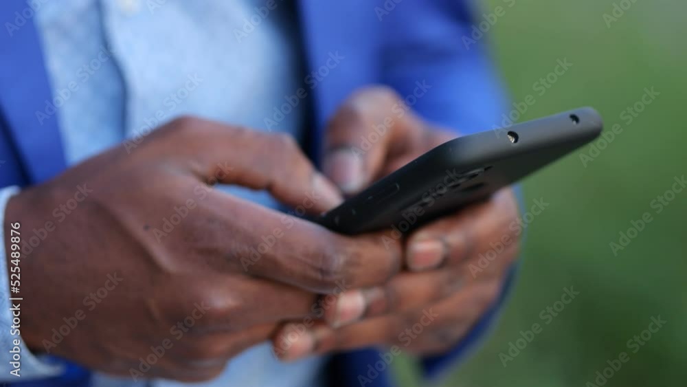 Black man wearing blue blazer hands enter necessary information into modern smartphone. African American person works as entrepreneur outdoors Black man wearing blue blazer hands enter necessary information into modern smartphone. African American person works as entrepreneur outdoors