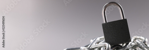 Solid metal locked padlock on top of tangled silver chain