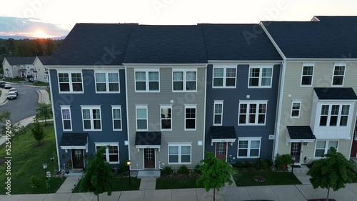 New construction. Residential town homes and apartment buildings. Rising aerial of sunset on horizon. Colorful siding. Life in community. photo