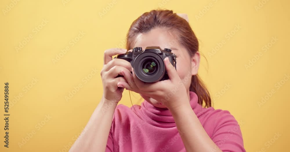 Asian gorgeous young woman in a studio shot over an isolated yellow background using a digital camera with copy space for advertising. Asian gorgeous young woman in a studio shot over an isolated yellow background using a digital camera with copy space for advertising.