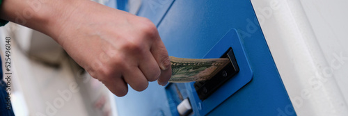 Hand inserting dollar money into bill acceptor closeup photo