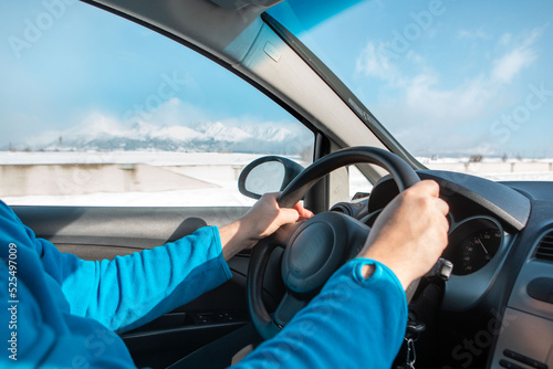 man hands on steering wheel winter road trip