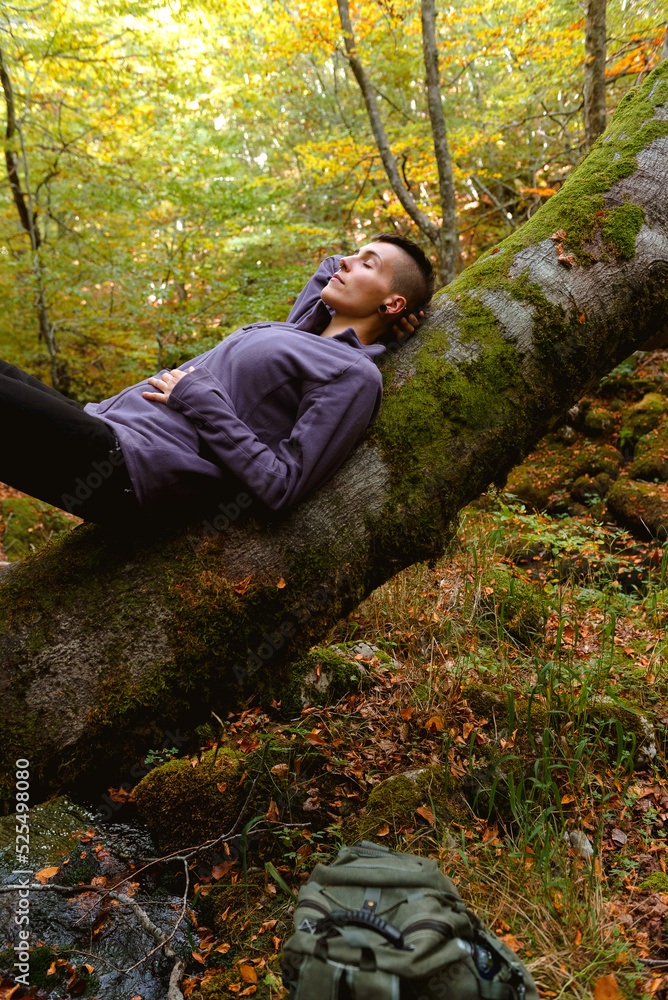 Woman lying on tree in autumnal forest