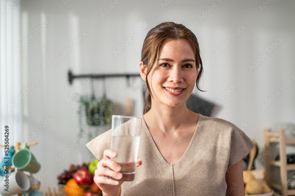 Portrait of Asian attractive woman drink a glass of water in kitchen. Portrait of Asian attractive woman drink a glass of water in kitchen.