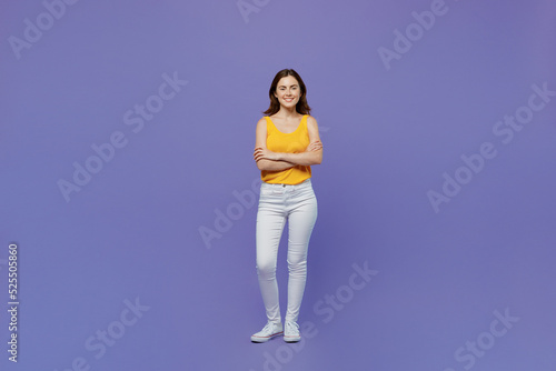 Full body young smiling happy fun woman 20s she wear yellow tank shirt hold hands crossed folded look camera isolated on plain pastel light purple background studio portrait. People lifestyle concept.