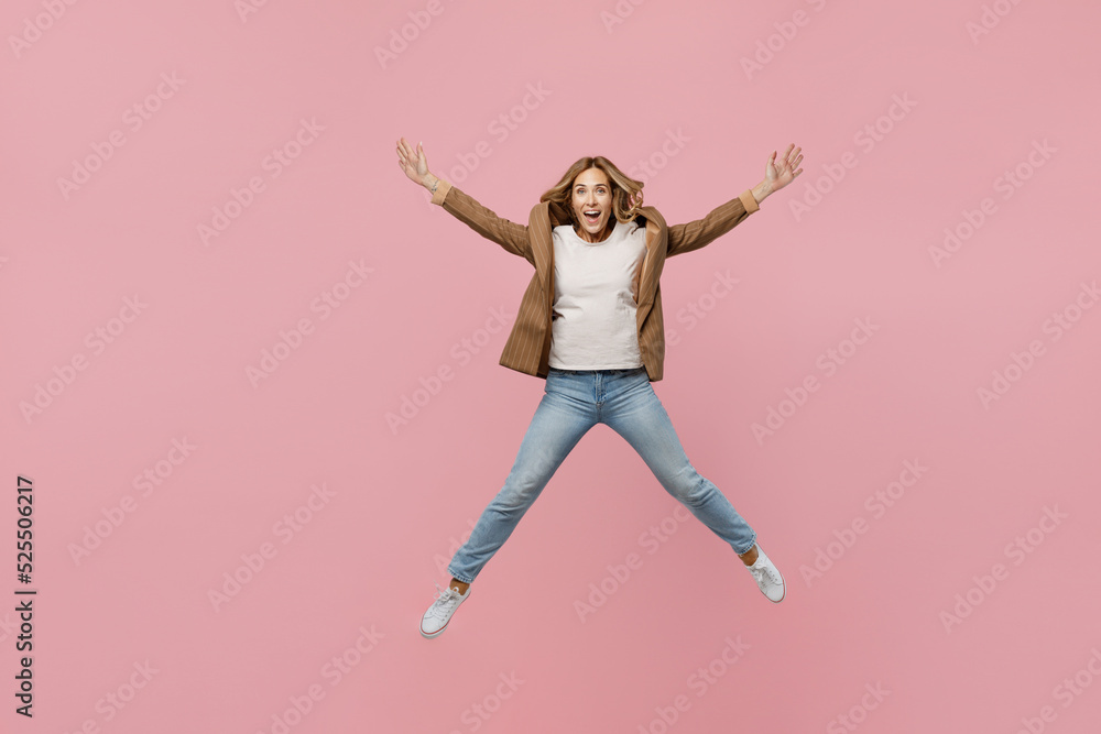 Full body young fun overjoyed successful employee business woman 30s she wear casual brown classic jacket jump high with outstretched hands legs isolated on plain pastel light pink background studio.