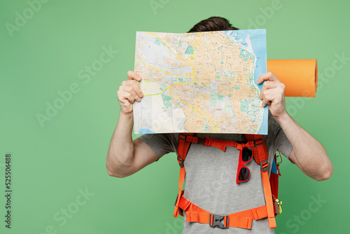 Young traveler white man carry backpack stuff mat cover gace with map isolated on plain green background Tourist leads active healthy lifestyle walk on spare time Hiking trek rest travel trip concept photo