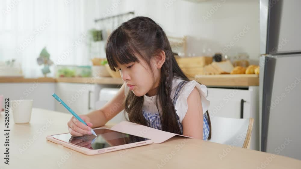 Asian young kid girl coloring and painting on tablet in living room. Asian young kid girl coloring and painting on tablet in living room.