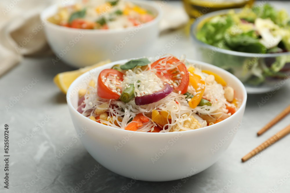 Tasty cooked rice noodles with vegetables on grey marble table Tasty cooked rice noodles with vegetables on grey marble table