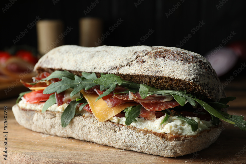Delicious sandwich with fresh vegetables and prosciutto on wooden table, closeup