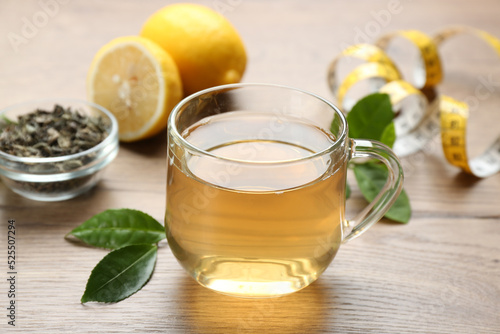 Herbal diet tea, lemon and measuring tape on wooden table