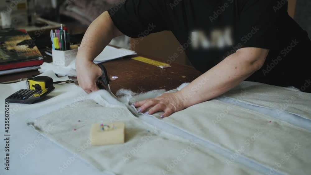 Close-up female hands cutting foam rubber with scissors for the production of a sofa in a furniture factory, slow motion shot. Close-up female hands cutting foam rubber with scissors for the production of a sofa in a furniture factory, slow motion shot.
