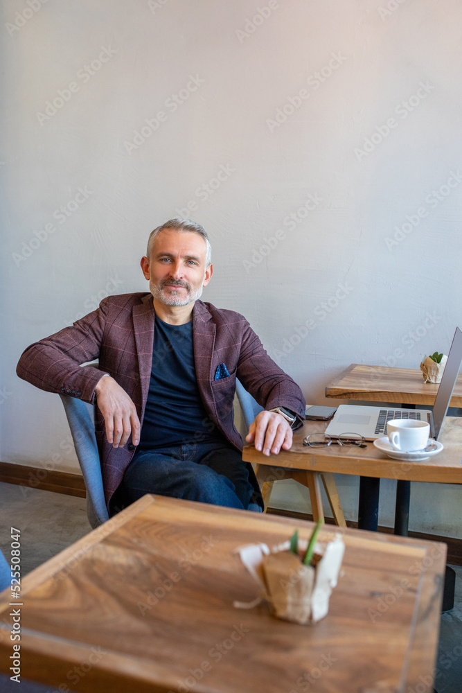 Confident man in jacket sitting in a cafe and looking in camera