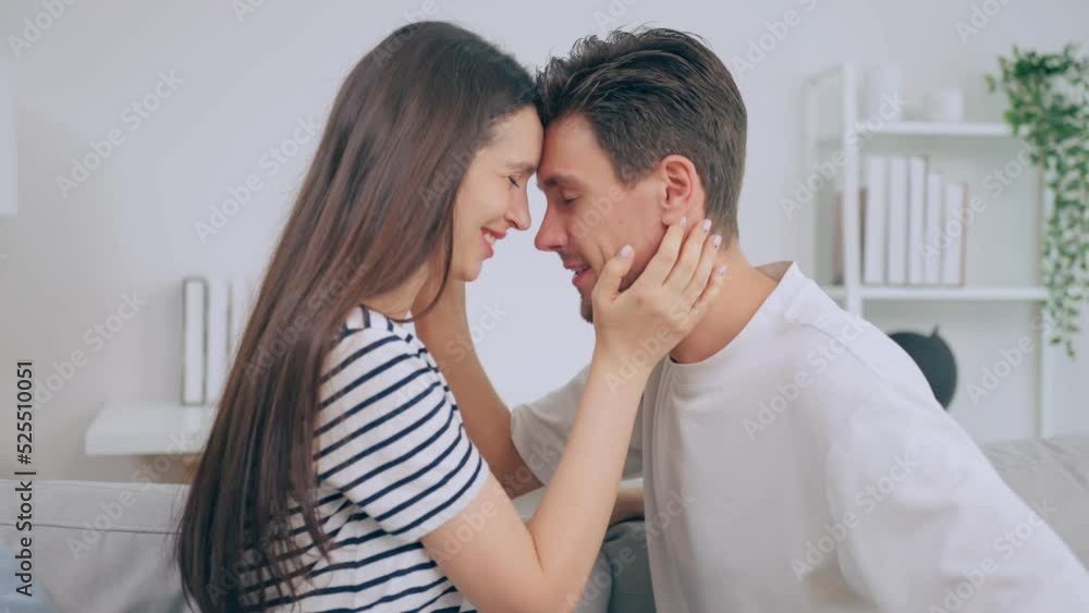 Caucasian young man and woman kissing each other in living room at home Caucasian young man and woman kissing each other in living room at home