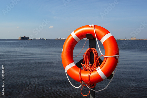 Orange lifebuoy hanging on the background of the blue sea