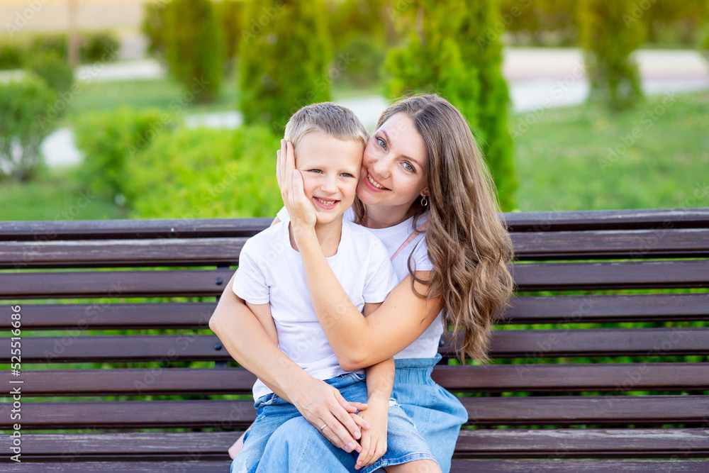 mom and her baby son in the park on a bench in the summer have fun hugging, laughing and playing mom and her baby son in the park on a bench in the summer have fun hugging, laughing and playing