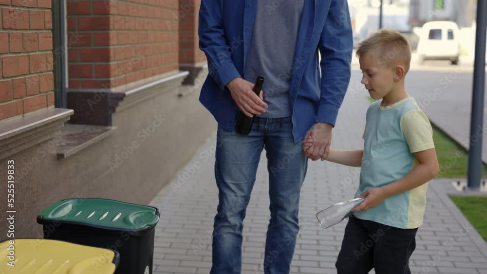 Dad teaches his son to properly sort garbage. Father shows his son where to properly throw away glass. Ecology and environmental problems concept Dad teaches his son to properly sort garbage. Father shows his son where to properly throw away glass. Ecology and environmental problems concept