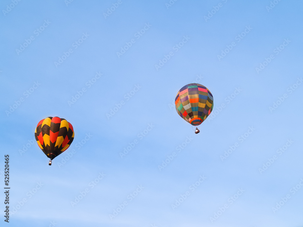 Obraz premium Highly coloured hot air balloons high up in blue sky.