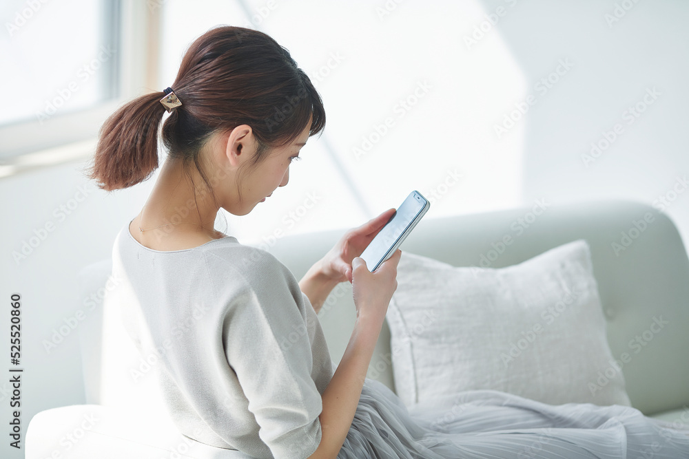 リビングでスマートフォンを使う女性 リビングでスマートフォンを使う女性