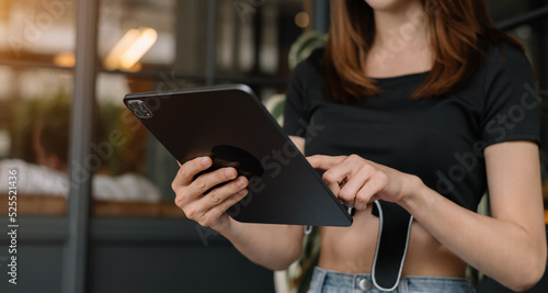 woman touching on tablet screen while standing in blurred office background.