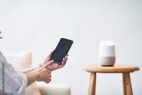 スマートスピーカーとスマートフォンと女性の手