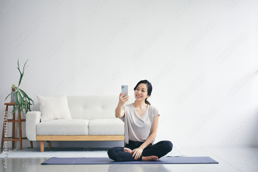 室内でスマートフォンを持ち運動する女性