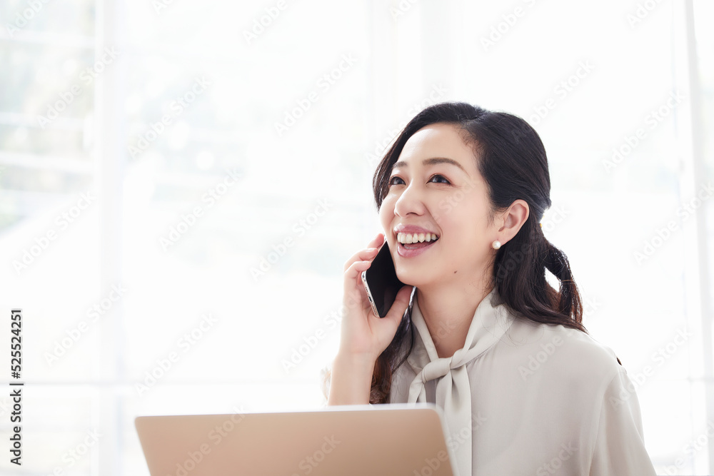 スマートフォンを持ちながら仕事をする女性 スマートフォンを持ちながら仕事をする女性
