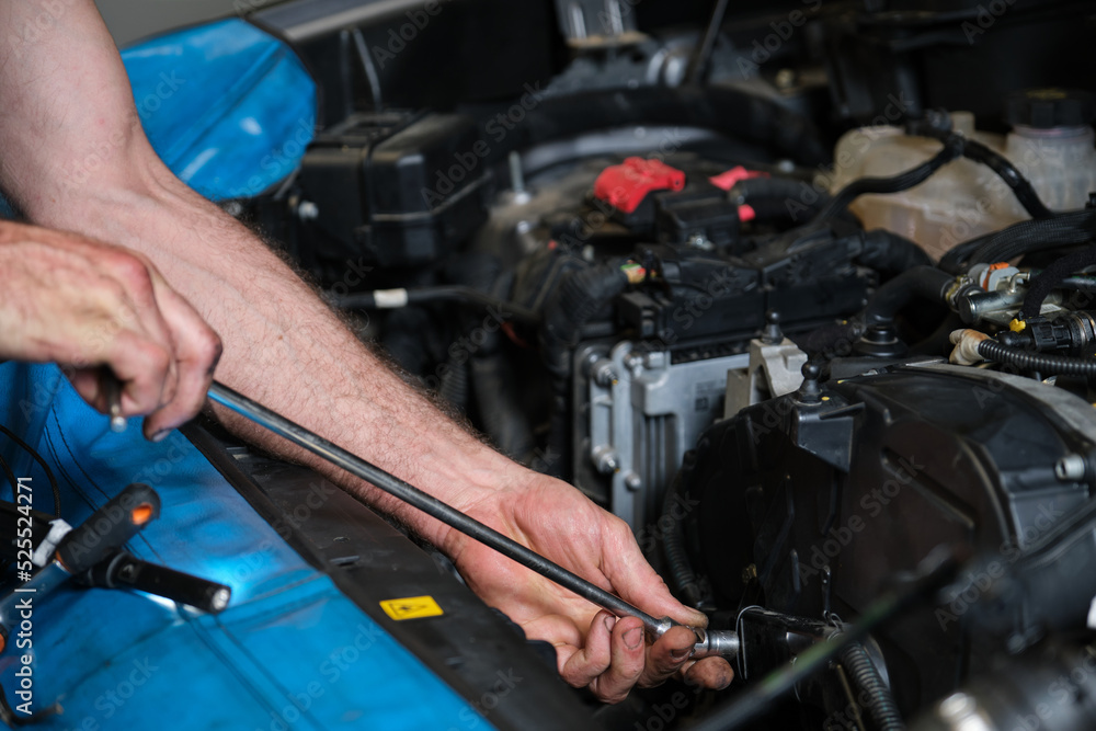 Auto mechanic hands unscrews the engine mount to replace the timing belt. Mechanics workshop. Auto mechanic hands unscrews the engine mount to replace the timing belt. Mechanics workshop.