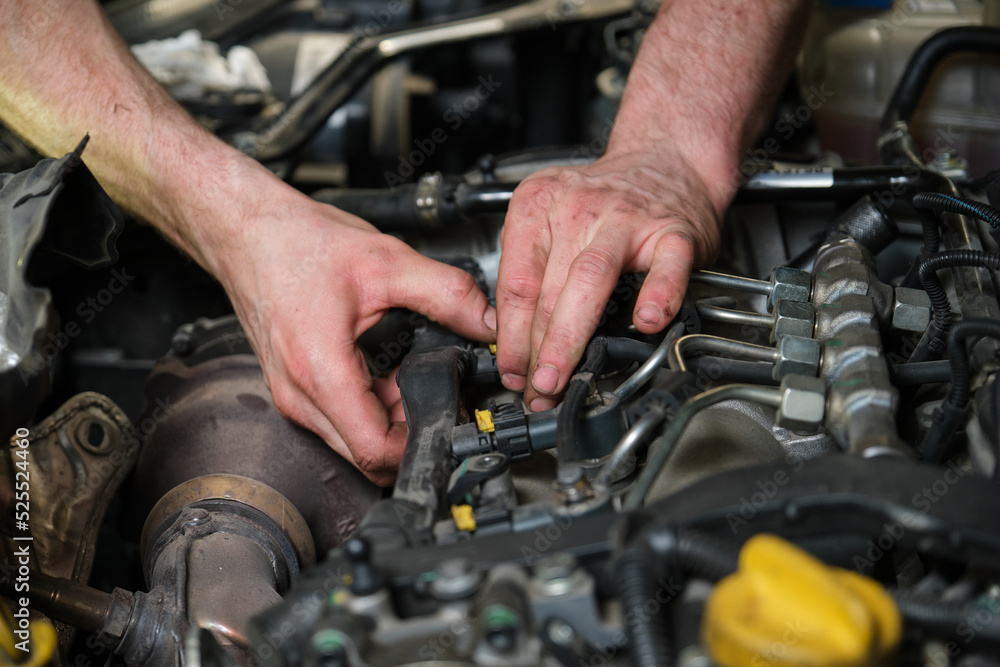 Close up of car mechanic hands removing fuel injectors in engine room checking dust and test pressure in maintenance process. Close up of car mechanic hands removing fuel injectors in engine room checking dust and test pressure in maintenance process.
