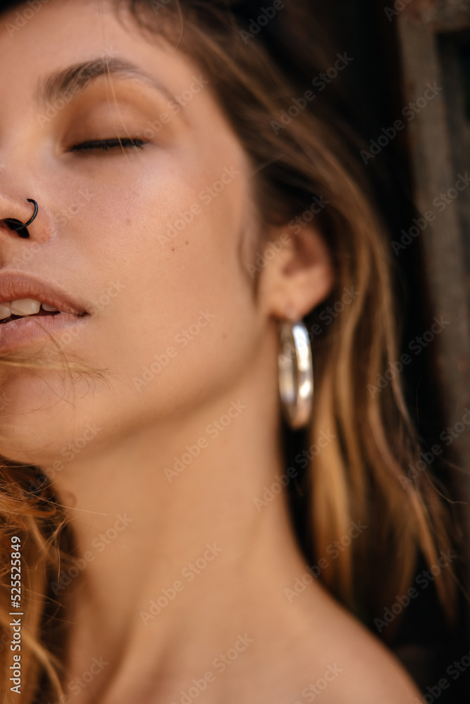 Obraz premium Close-up of satisfied young caucasian woman with piercings and closed eyes. Brown-haired girl spends her free time relaxed. Lifestyle concept