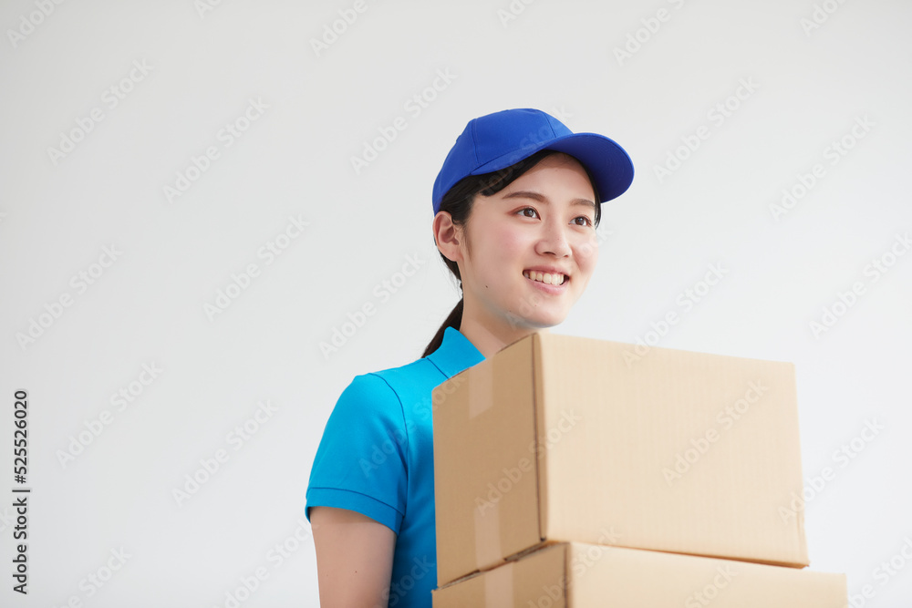 作業服を着て笑顔で荷物を運ぶ若い女性