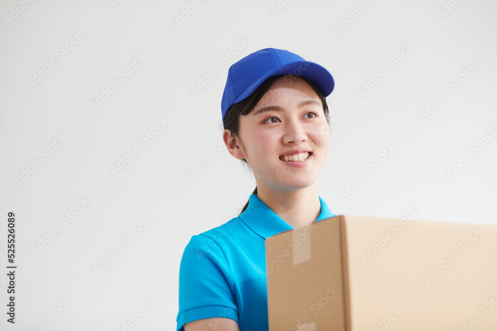 作業服を着て笑顔で荷物を運ぶ若い女性 作業服を着て笑顔で荷物を運ぶ若い女性