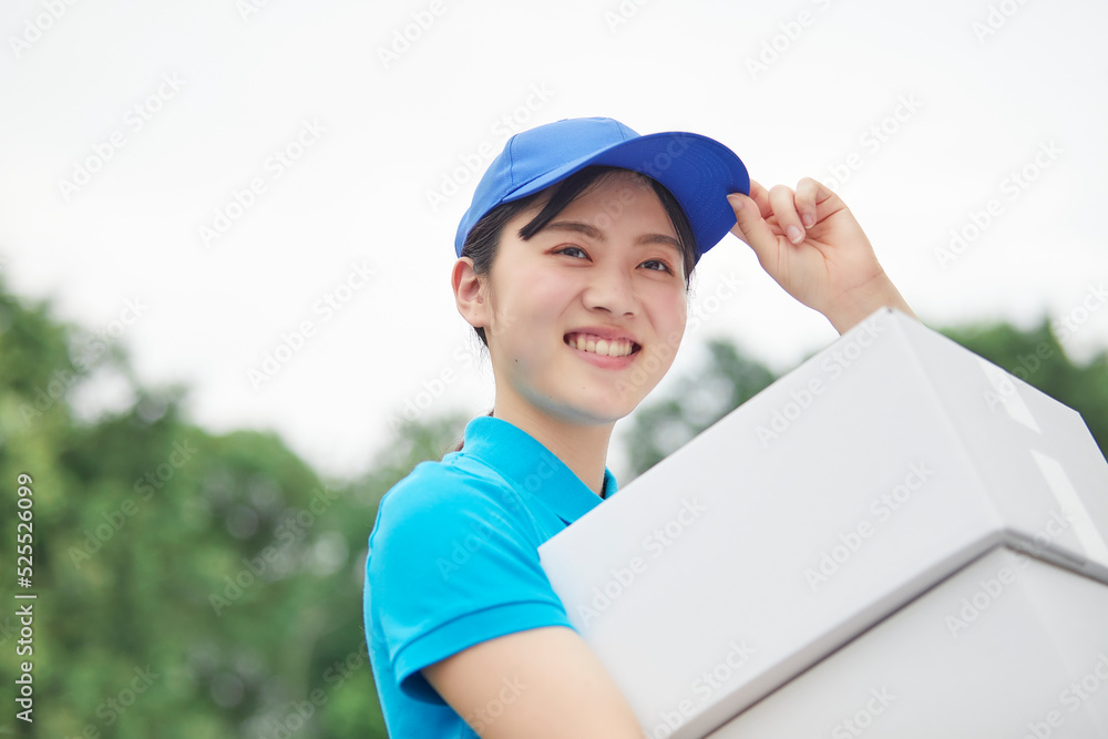 作業服を着て笑顔で荷物を運ぶ若い女性 作業服を着て笑顔で荷物を運ぶ若い女性