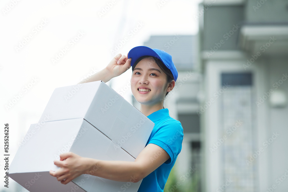 作業服を着て笑顔で荷物を運ぶ若い女性 作業服を着て笑顔で荷物を運ぶ若い女性