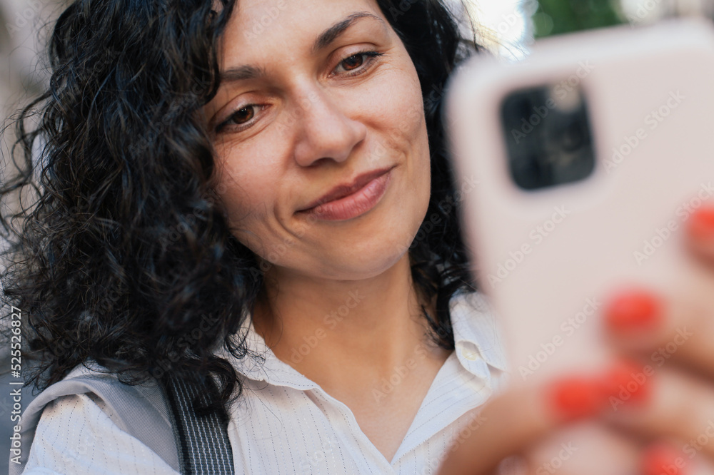 Close up portrait of a woman looking at her smartphone in pink case and smiling