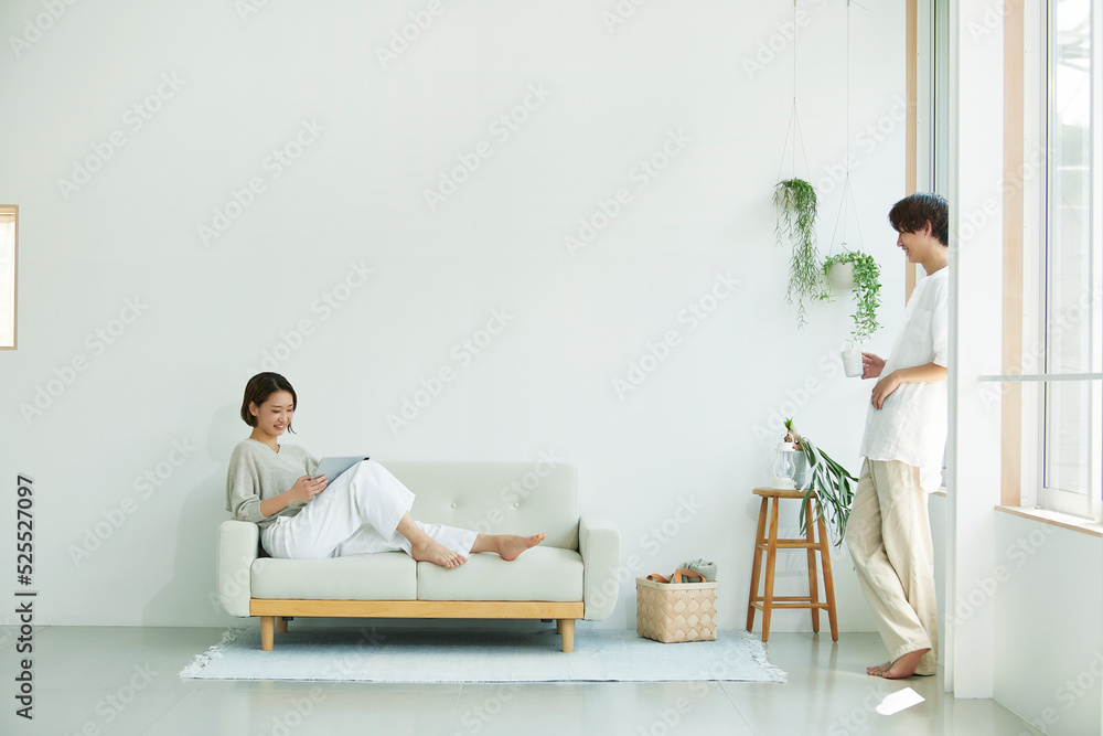 室内でソファに座りタブレットPCを見る若い女性と男性