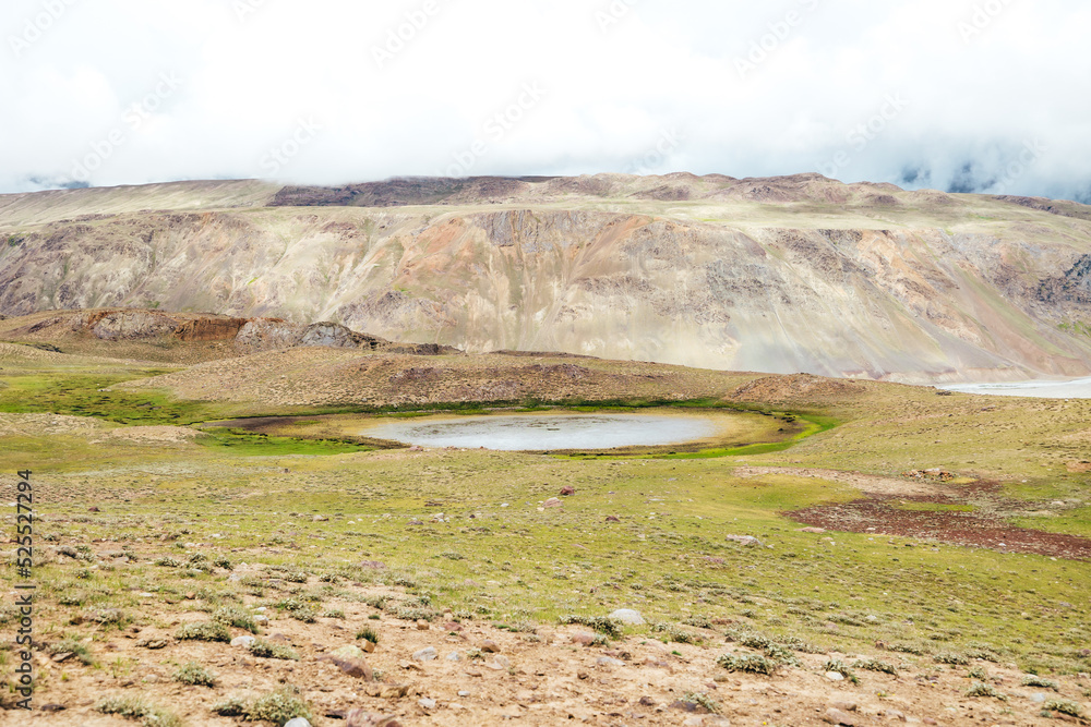 single remote sinkhole at Upper Chandra Taal Lake in Spiti Valley with mountain landscape