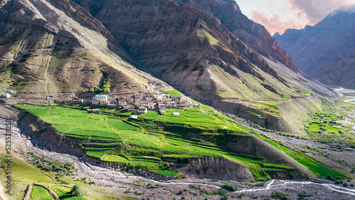 Aerial of Mud Village homes in the Mountains of Pin Valley in Himachal Pradesh with lush green farmland during an Indian summer
